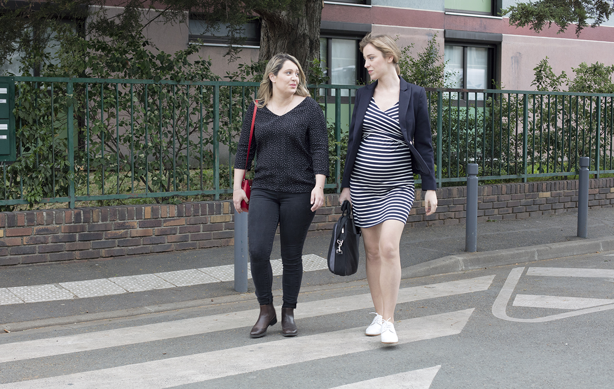 deux femmes actives dont une enceinte traversent la rue en discutant