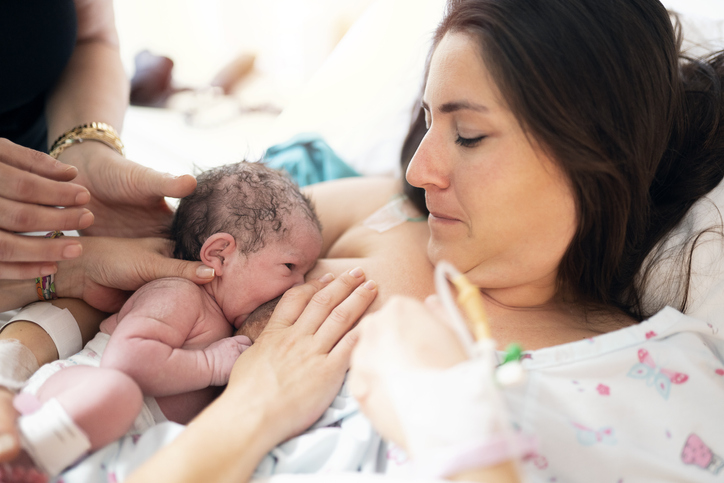 Femme qui allaite un nouveau-né avec l'aide d'une professionnelle